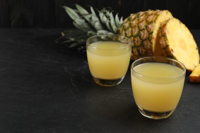 Delicious fresh pineapple juice on black table. Space for text