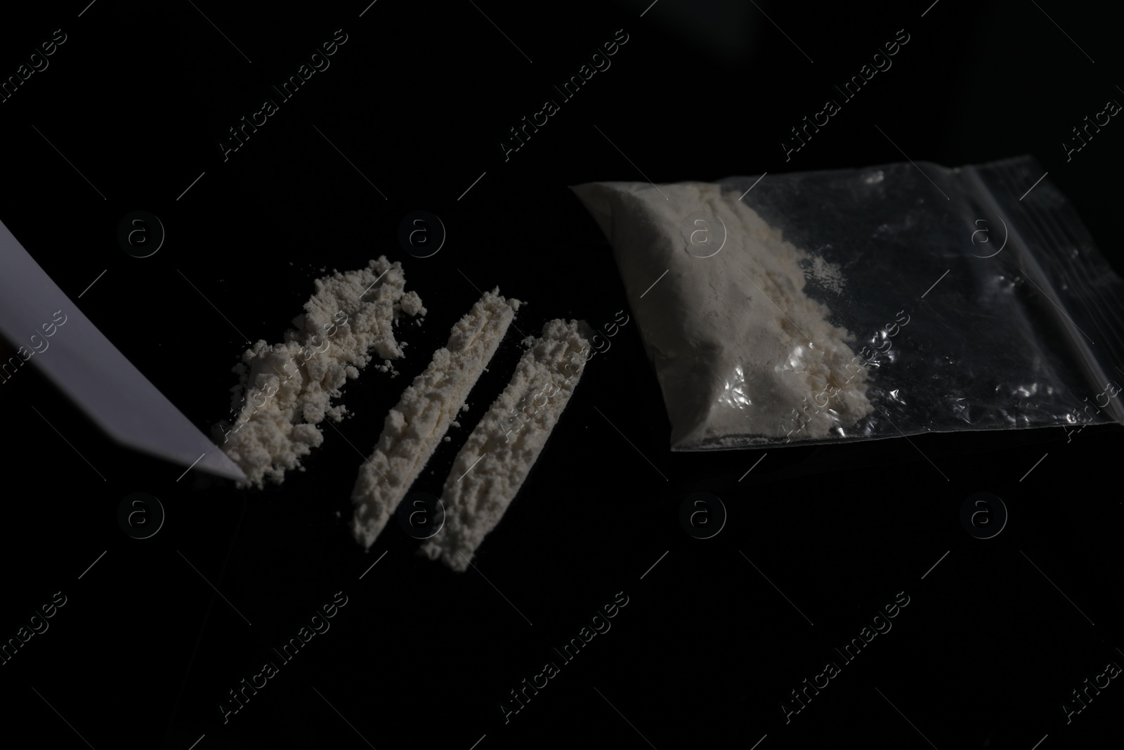 Photo of Drug addiction. Plastic bag with cocaine and blank card on black table