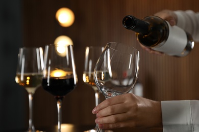 Photo of Waitress pouring wine into glass in restaurant, closeup