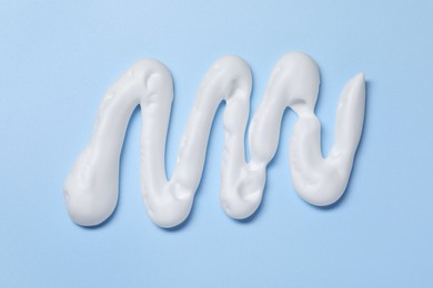 Photo of Sample of shaving foam on light blue background, top view