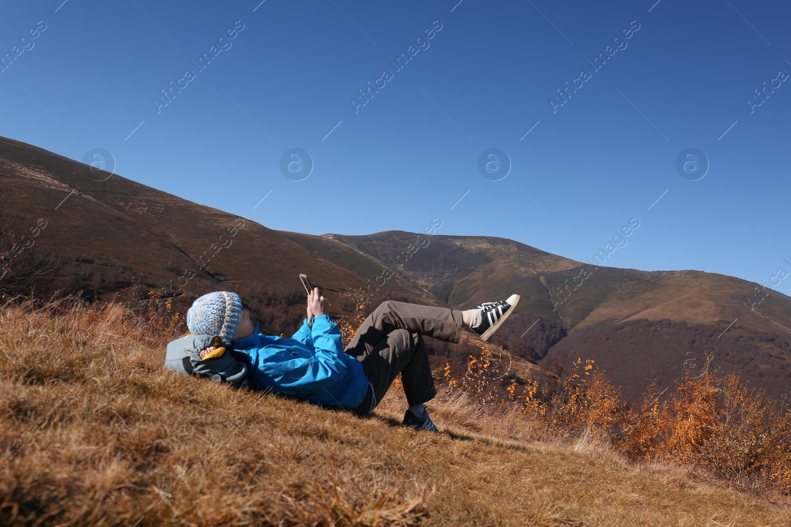 Photo of Woman in warm clothes relaxing on mountain slope