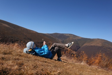 Woman in warm clothes relaxing on mountain slope