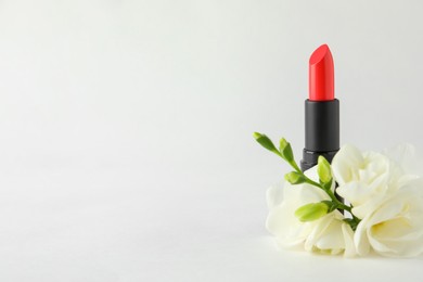 Photo of Beautiful lipstick and flowers on white background, space for text