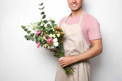 Photo of Florist with beautiful bouquet on light background, closeup