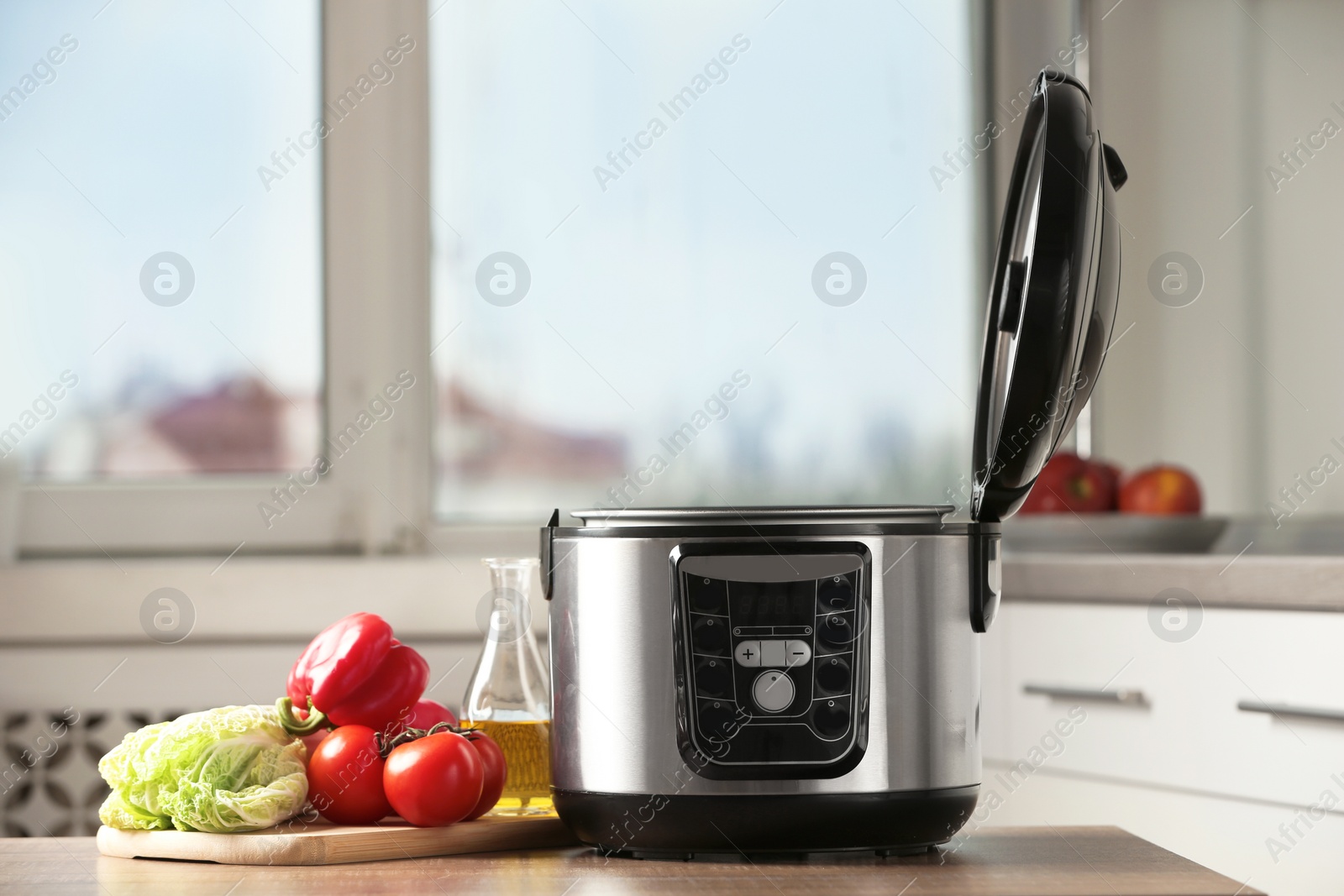Photo of Modern multi cooker and products on table in kitchen. Space for text