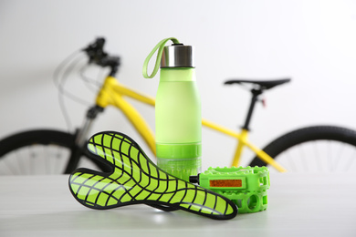 Photo of Bicycle saddle, bottle and pedals on white table