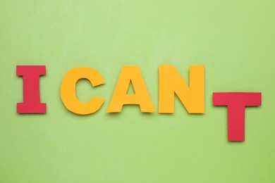 Photo of Motivation concept. Changing phrase from I Can't into I Can by removing letter T on light green background, flat lay