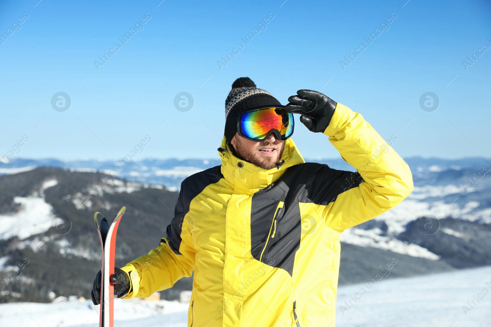 Photo of Happy man with ski equipment in mountains. Winter vacation