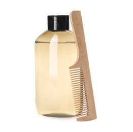 Bottle of shampoo and wooden comb on white background