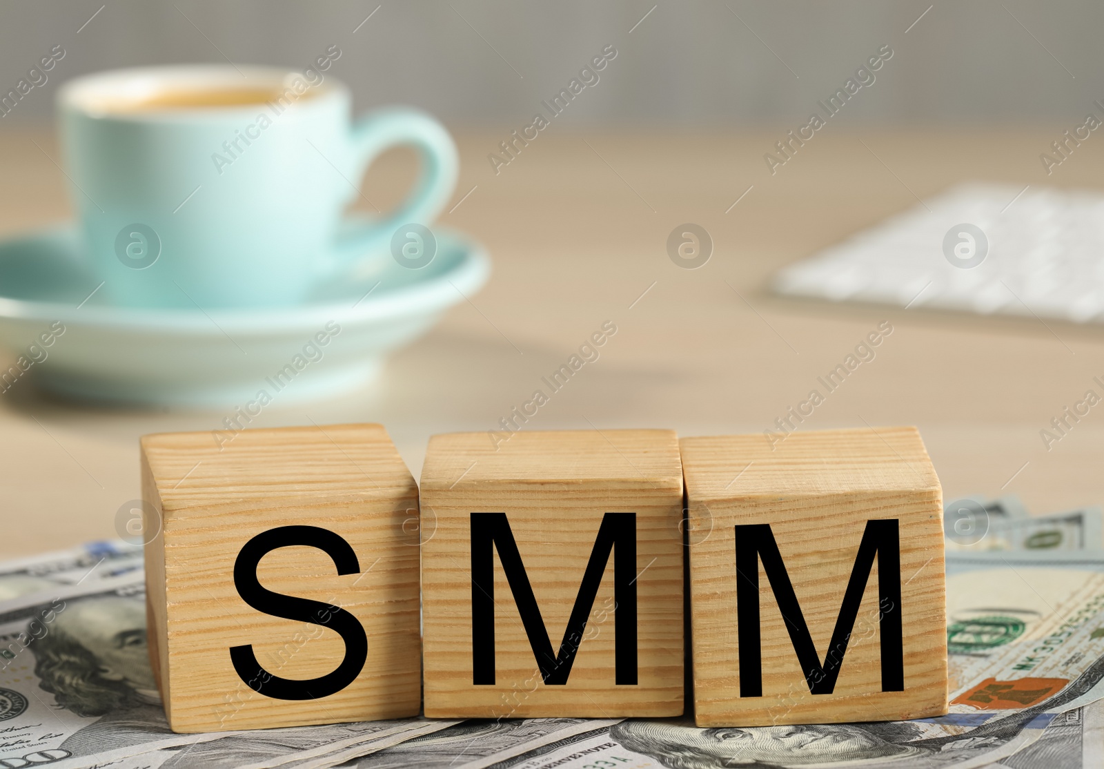 Photo of Cubes with letters SMM and dollar banknotes on wooden table