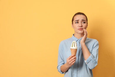 Photo of Emotional young woman with sensitive teeth and ice cream on color background. Space for text