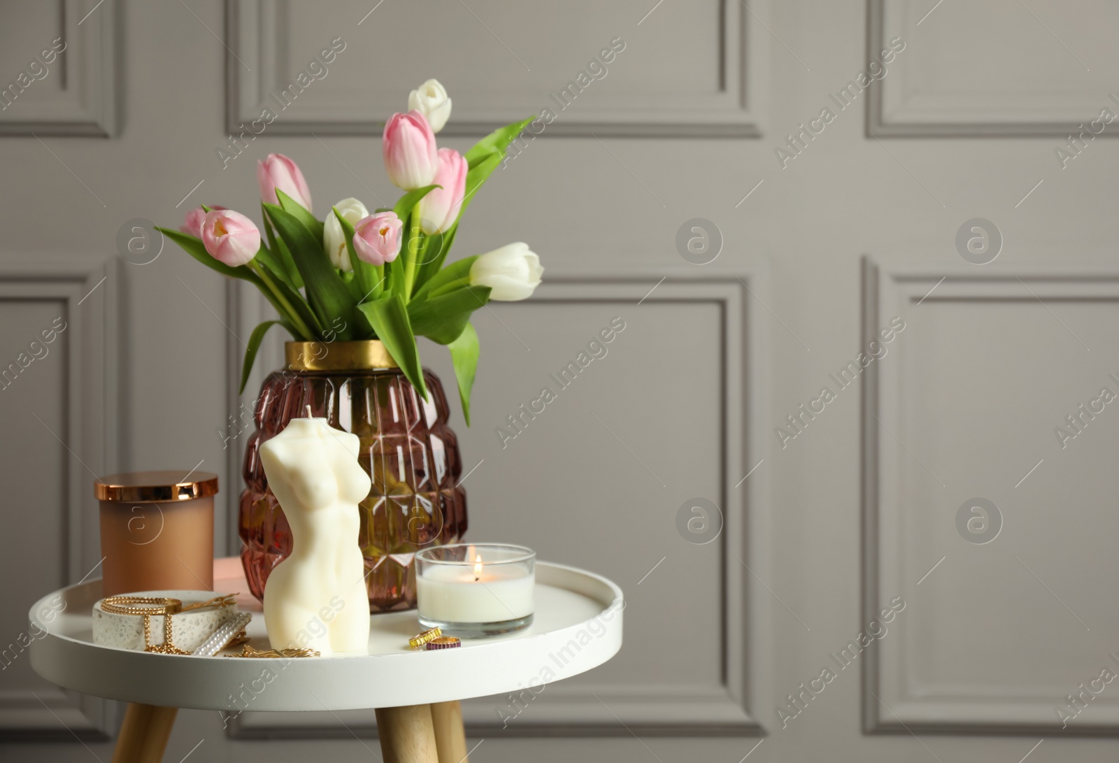 Photo of Beautiful female body shape candle, flowers and decor on white table. Space for text