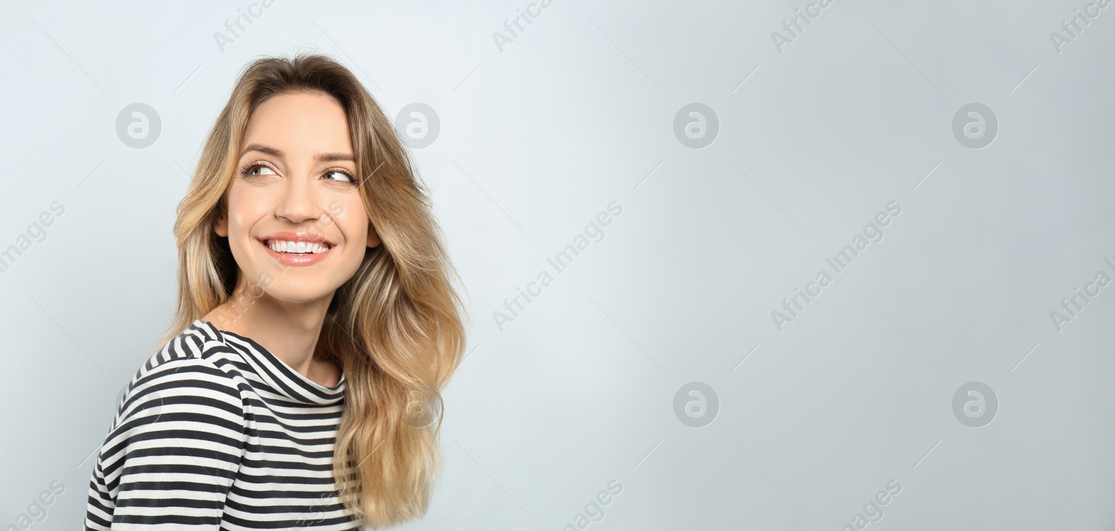 Photo of Portrait of happy young woman with beautiful blonde hair and charming smile on light background. Space for text