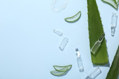 Photo of Flat lay composition with skincare ampoules and aloe leaves on light blue background. Space for text