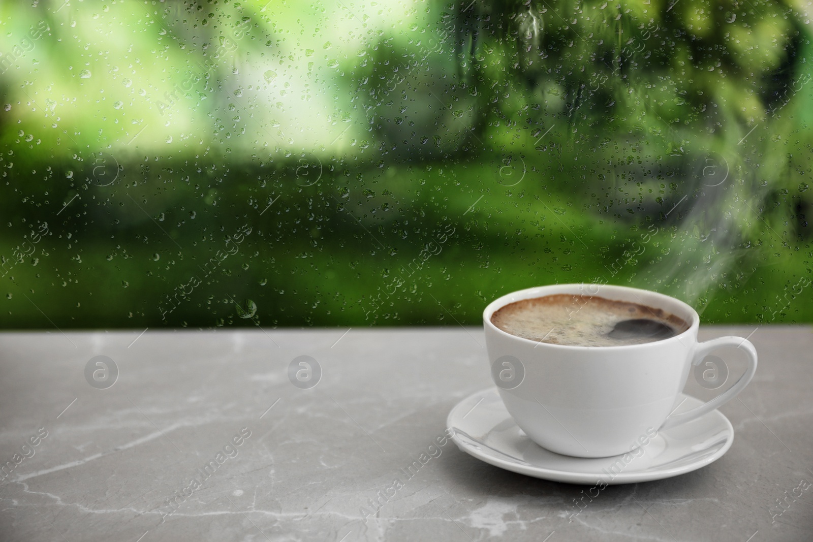 Image of Cup of hot drink near window on rainy day