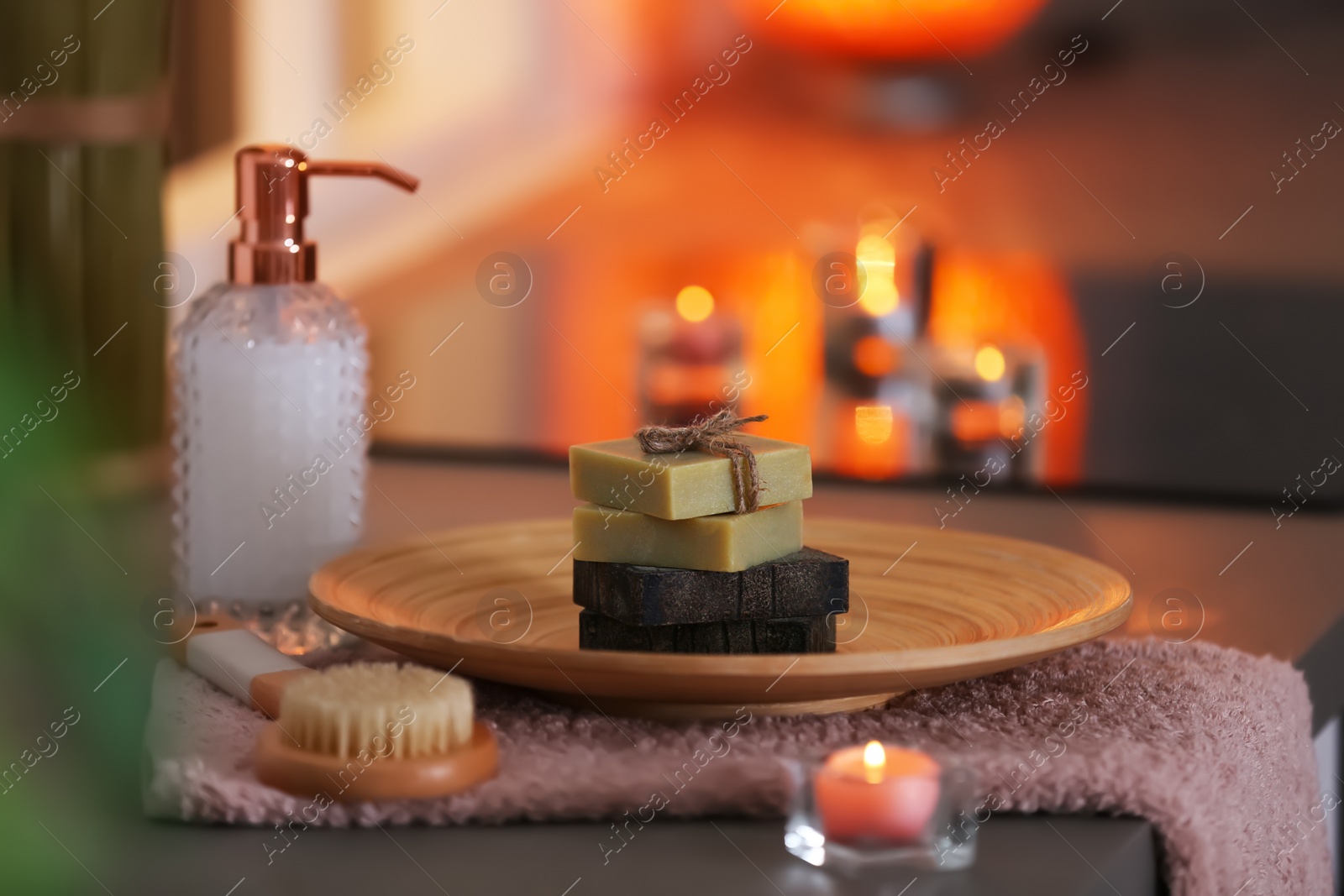 Photo of Bottle of shampoo and soap bars on table against blurred background