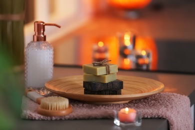 Photo of Bottle of shampoo and soap bars on table against blurred background