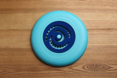 Photo of Blue plastic frisbee disk on wooden background, top view