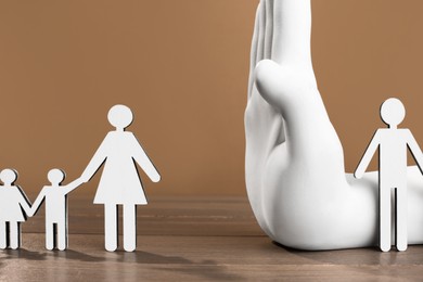 Divorce concept. Hand model dividing paper figures of woman with children and man on wooden table