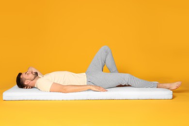 Man sleeping on soft mattress against orange background