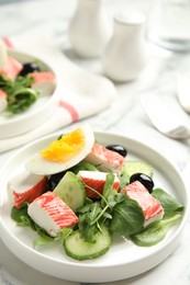 Photo of Delicious crab stick salad on white plate, closeup