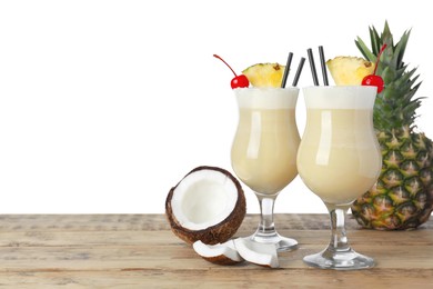 Tasty Pina Colada cocktail and ingredients on wooden table against white background, space for text