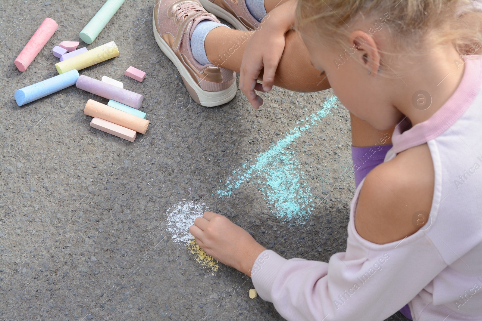 Photo of Little child drawing flower with chalk on asphalt, closeup