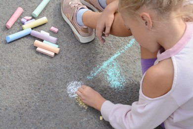 Photo of Little child drawing flower with chalk on asphalt, closeup