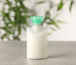 Photo of Mini bottle of cosmetic product on light grey table against blurred background