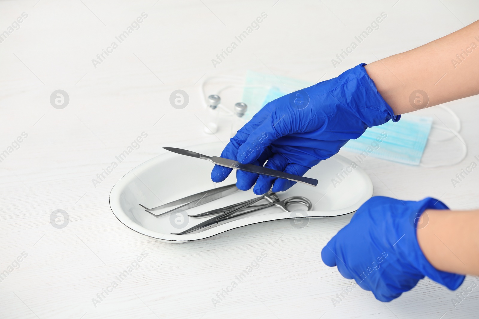 Photo of Doctor in sterile gloves with medical tools at table