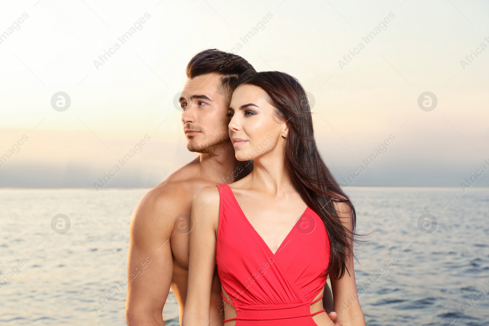 Photo of Young man and his beautiful girlfriend in bikini on yacht. Happy couple during sea trip