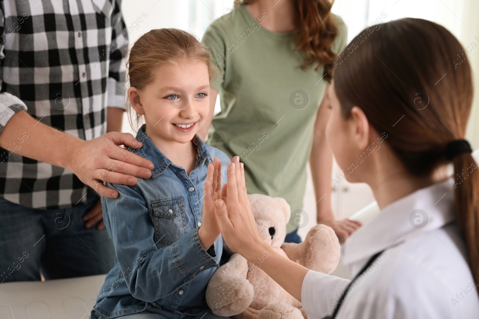 Photo of Parents and daughter visiting pediatrician. Doctor working with patient in hospital