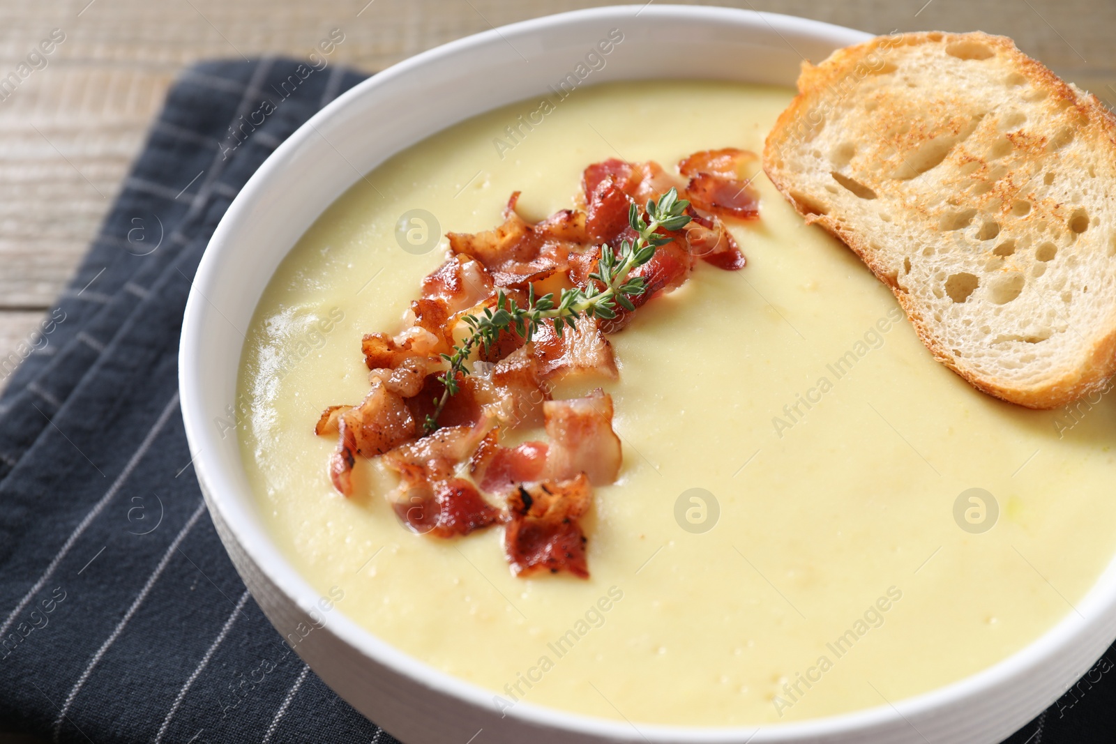 Photo of Tasty potato soup with bacon and crouton in bowl on table, closeup