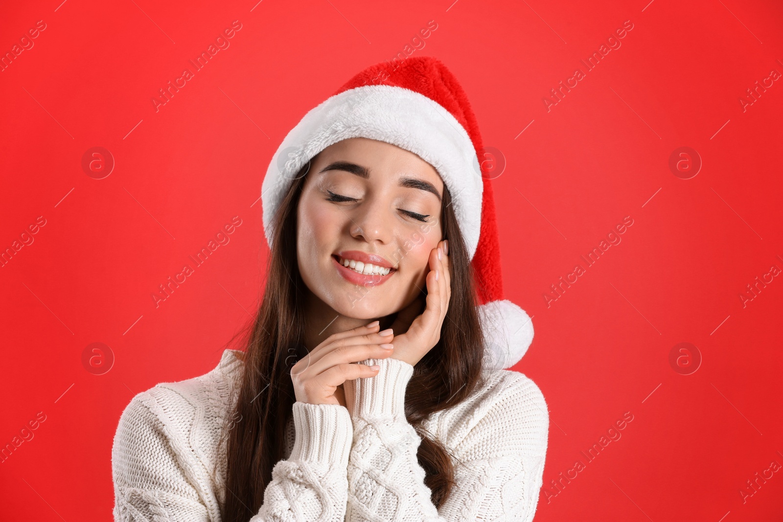 Photo of Beautiful woman wearing Santa Claus hat on red background
