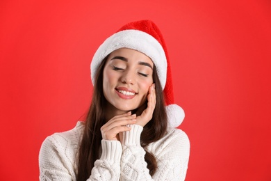 Photo of Beautiful woman wearing Santa Claus hat on red background