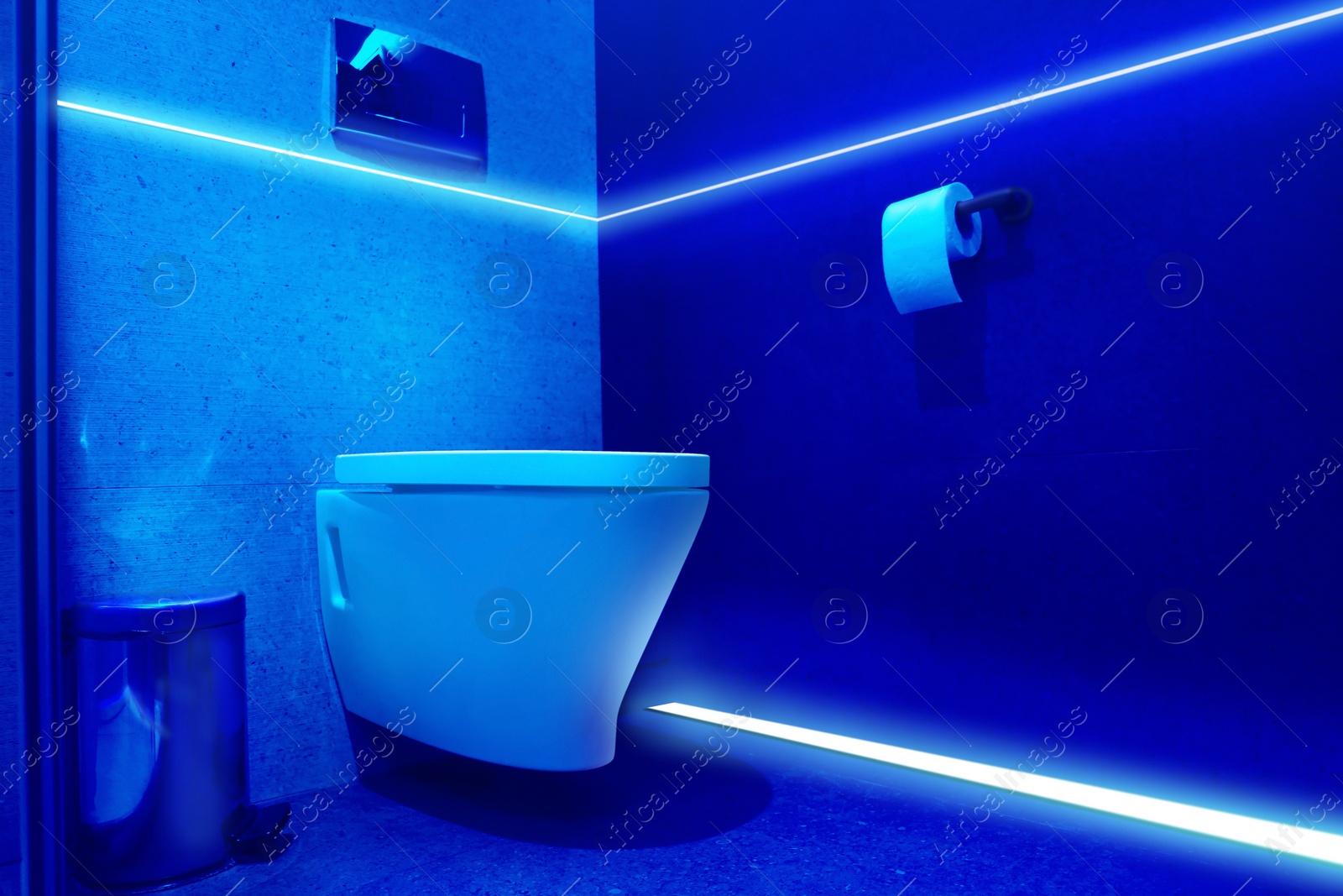 Image of Toilet bowl in public restroom lit with UV blue light