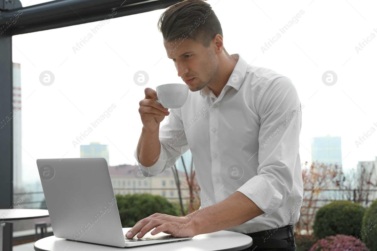 Photo of Businessman with laptop and coffee in outdoor cafe. Corporate blog