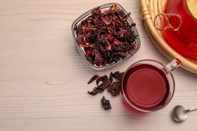 Delicious hibiscus tea and dry flowers on white wooden table, flat lay. Space for text