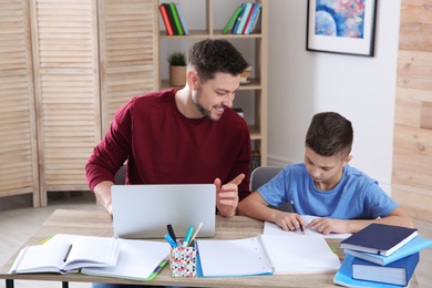 Dad helping his son with homework in room