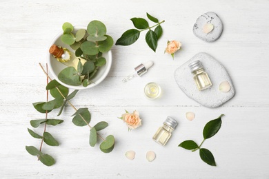 Flat lay composition with essential oil and ingredients on wooden background