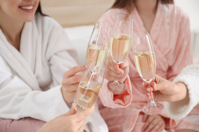 Photo of Beautiful young ladies clinking glasses of champagne at pamper party, closeup. Women's Day