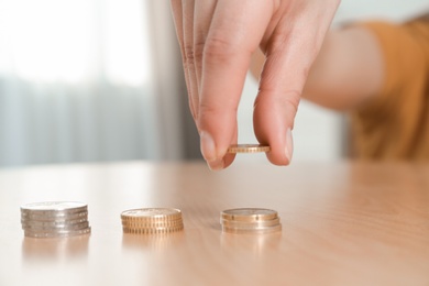 Woman stacking coins at table, focus on hand. Space for text