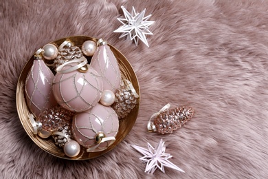 Photo of Christmas baubles on pink faux fur, flat lay