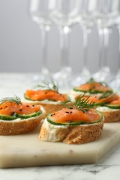 Photo of Tasty canapes with salmon, cucumber and cream cheese on white marble table, closeup