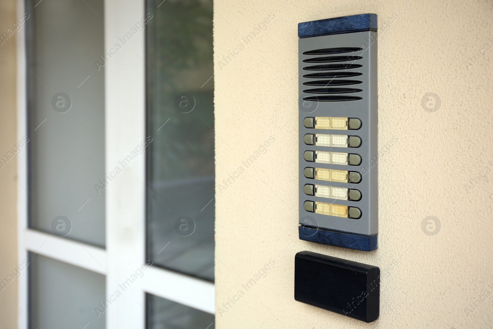 Photo of Modern intercom on beige wall near door outdoors, space for text