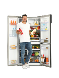 Man with sauces near open refrigerator on white background