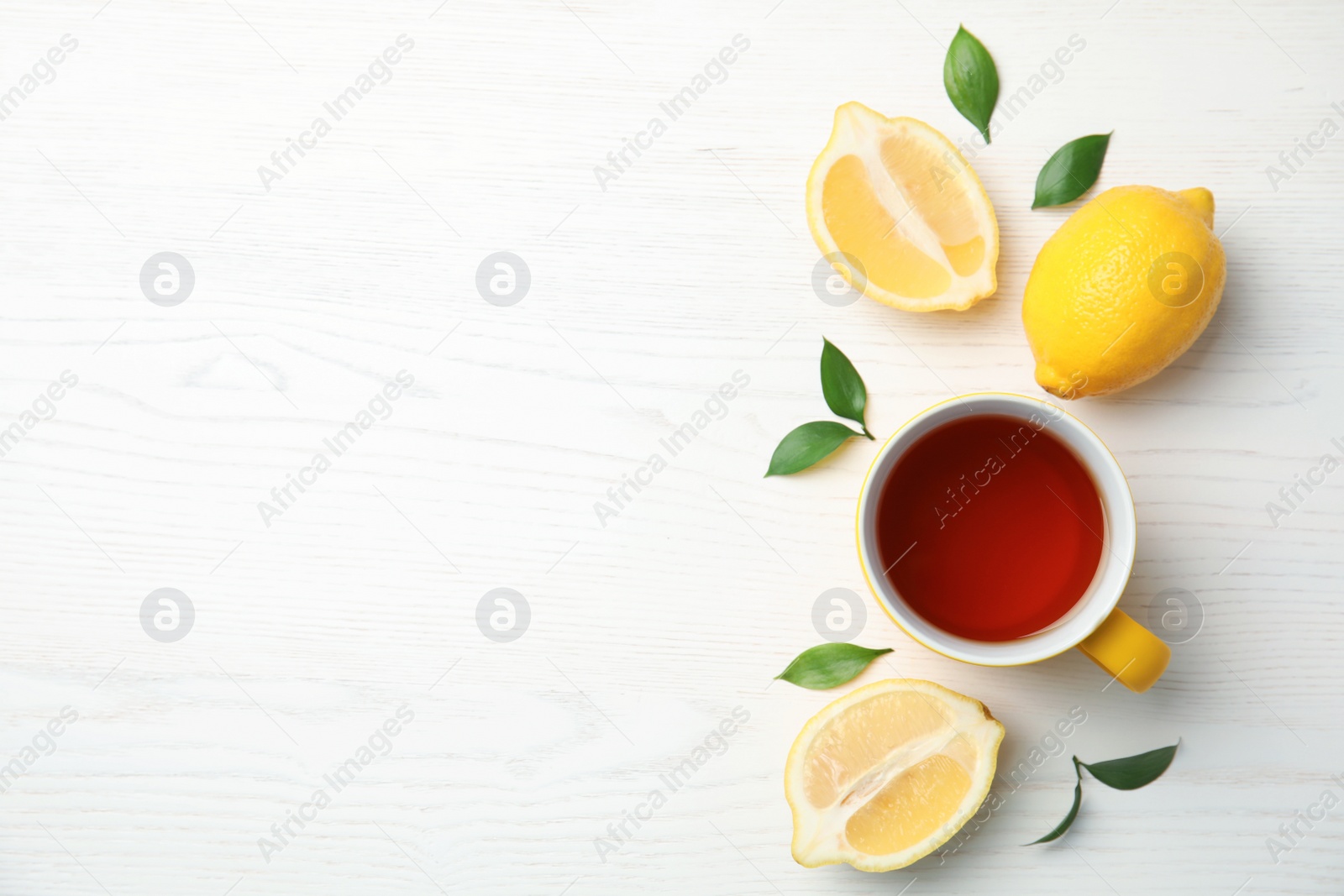 Photo of Cup of black tea and lemons on wooden table, top view