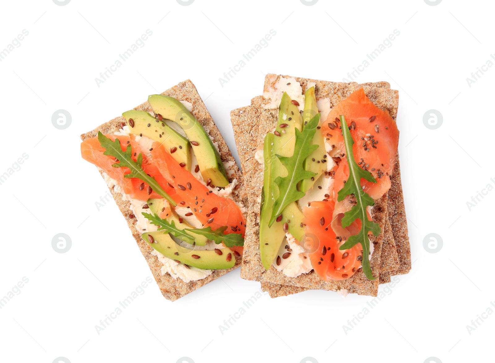 Photo of Fresh crunchy crispbreads with cream cheese, salmon, avocado and arugula isolated on white, top view