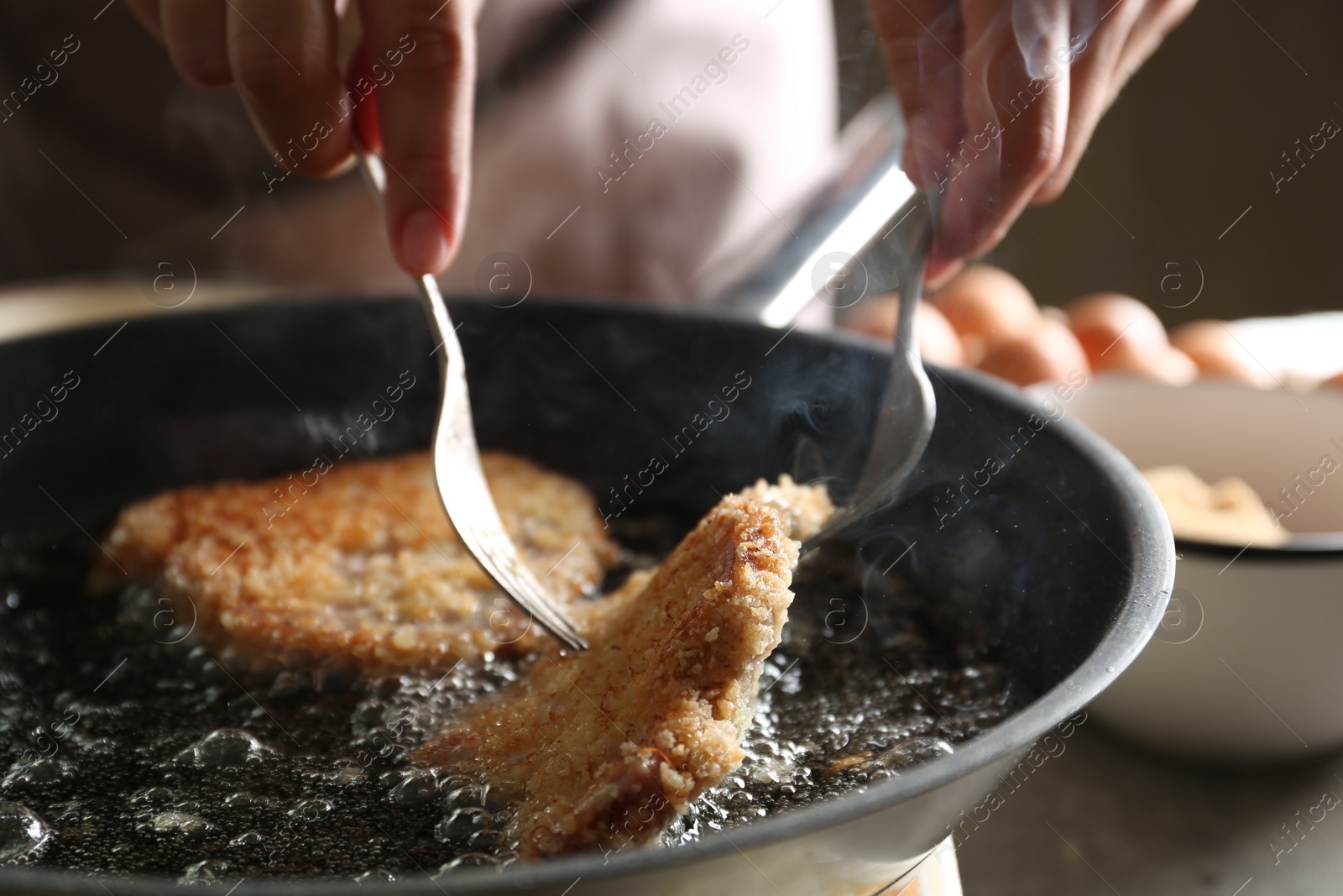 Photo of Woman cooking schnitzels in frying pan, closeup