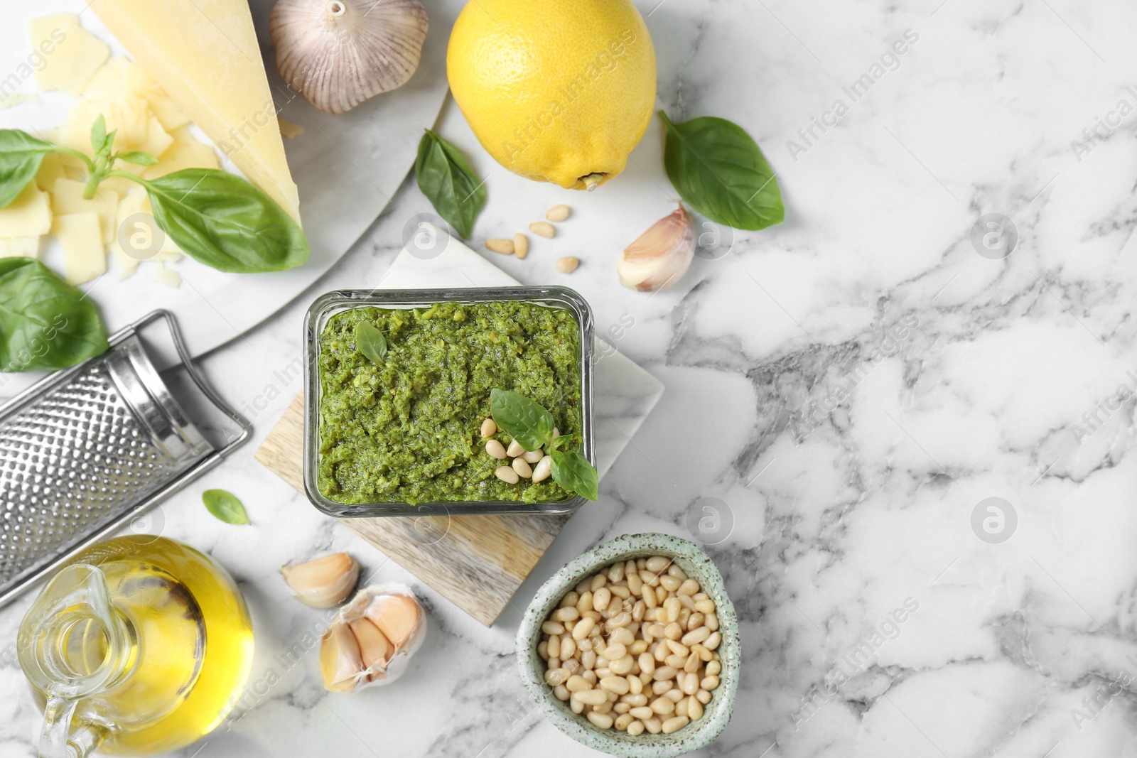 Photo of Flat lay composition with delicious pesto sauce and ingredients on white marble table. Space for text